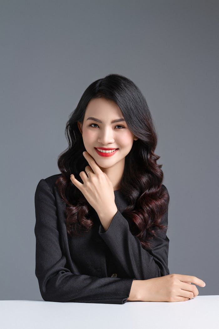 Studio portrait of an elegant smiling woman in a black outfit, showcasing beauty and confidence.